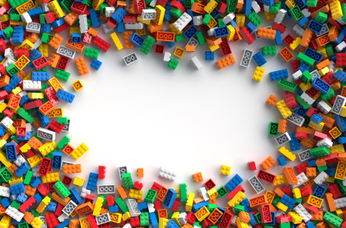 raztresene barvne lego kocke na beli podlagi, v sredini prazen prostor