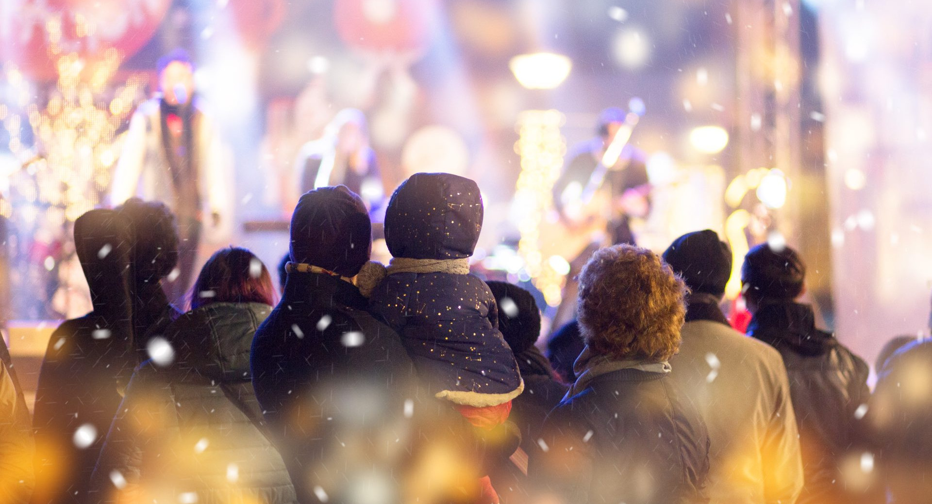 People photographed from behind are watching the Christmas lights in the city.