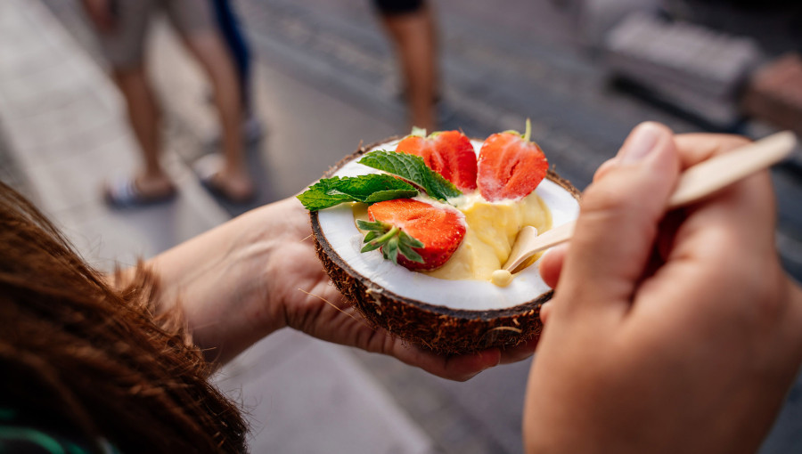 Eating a dessert in a coconut with a spoon.
