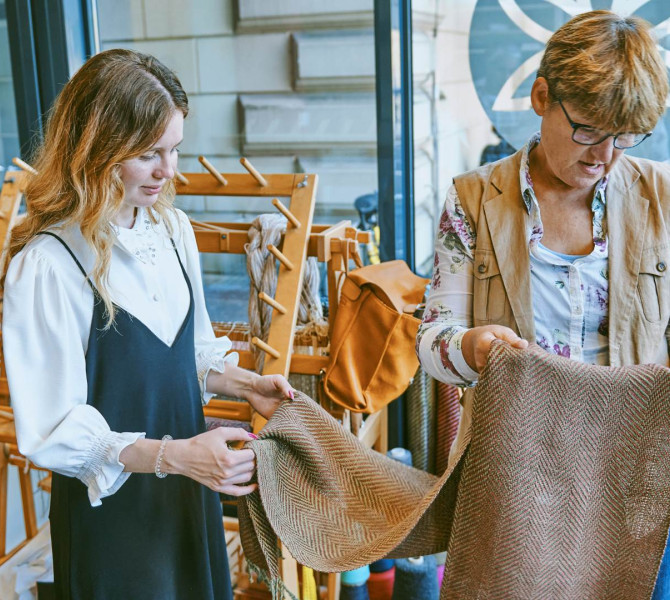 Two women are examining fabric at a weaving workshop.
