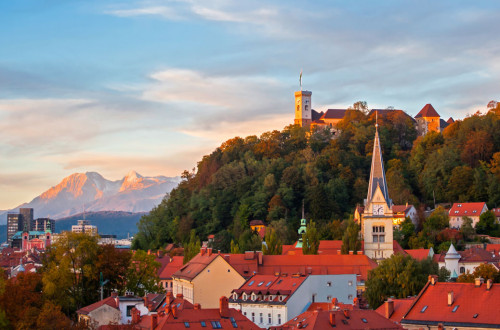 Ljubljanski grad nad strehami ljubljanskih hiš. V ozadju Alpe.
