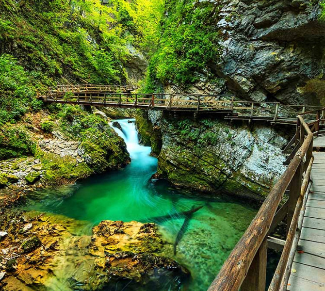 A gorge with a viewing path and an emerlad river.