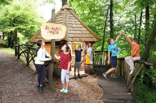 Obiskovalci pred hišico živalska koča. V ozadju drevesa.