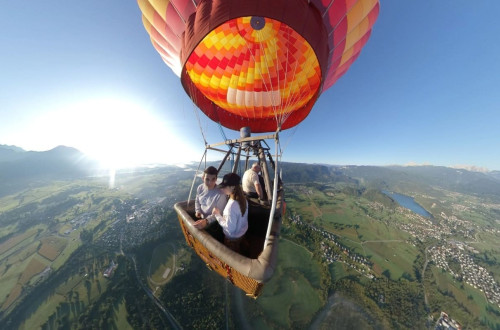 Three people flying with hot-air balloon over Lake Bled.