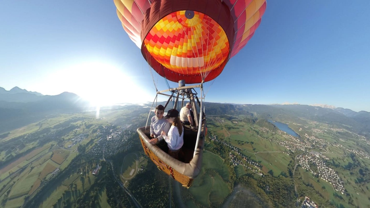 Three people flying with hot-air balloon over Lake Bled.