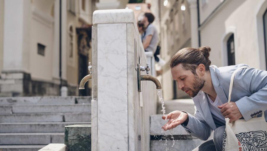  A man drinks water from a drinking fountain.