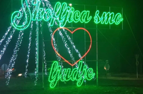 Praznicna svetlobna instalacija v zeleni barvi z rdecim srcem v sredini.