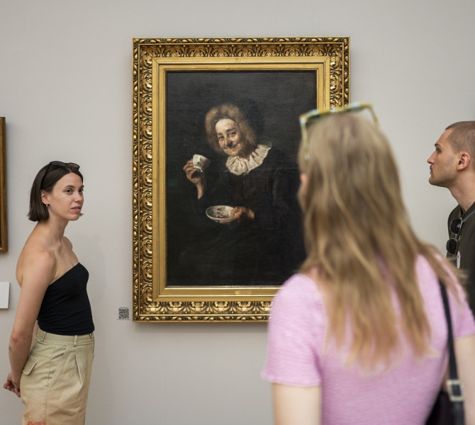 Three gallery visitors are looking at the painting "Kofetarica" on the wall.