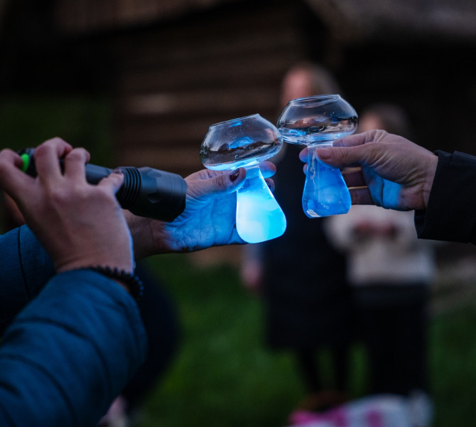 People toast with mushroom-shaped glasses, in which the drink glows blue under UV light.