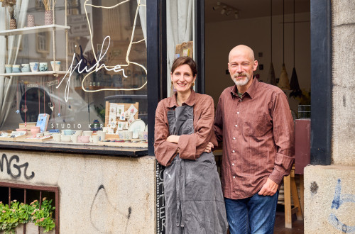  Dve osebi stojita pred vrati, ob izložbi s keramičnimi izdelki.