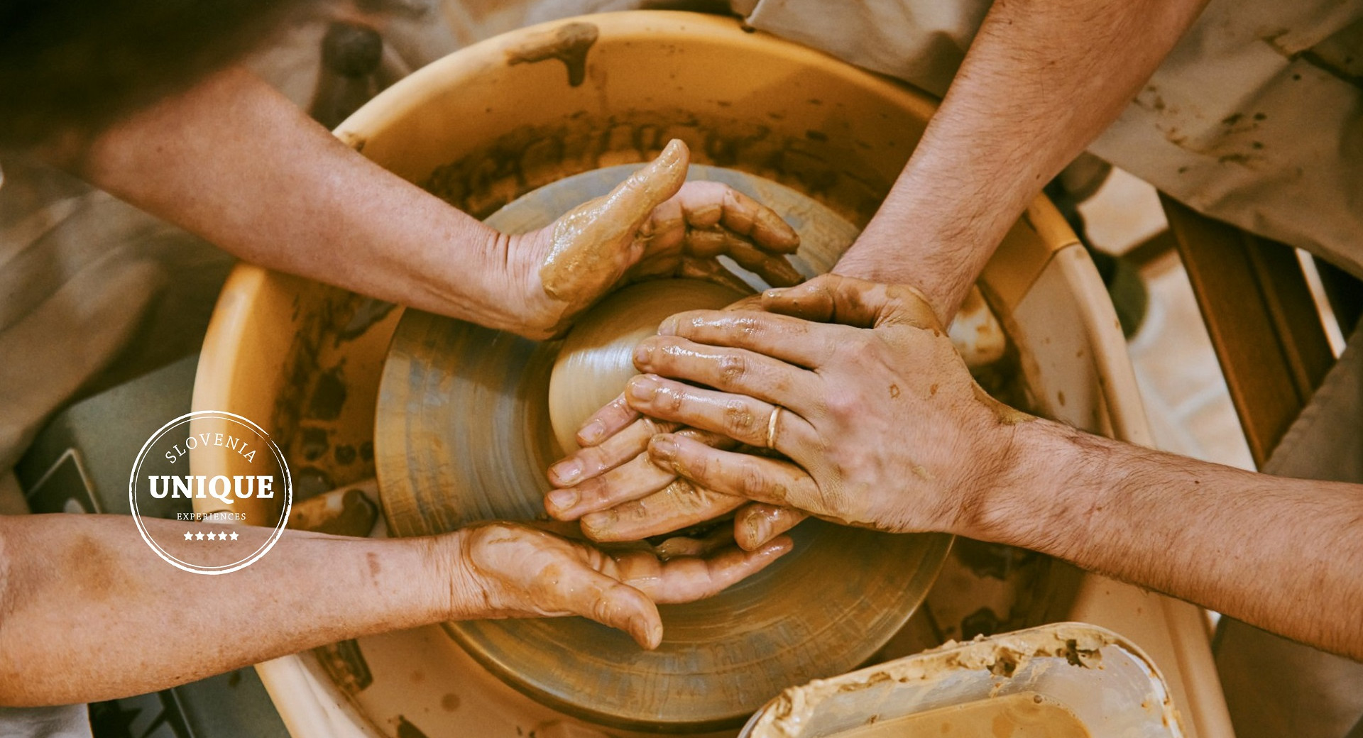 Deux paires de mains façonnent une tasse en argile sur un tour de potier.