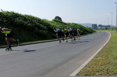 Rollerbladers are skating down a closed, empty road on their rollerblades.