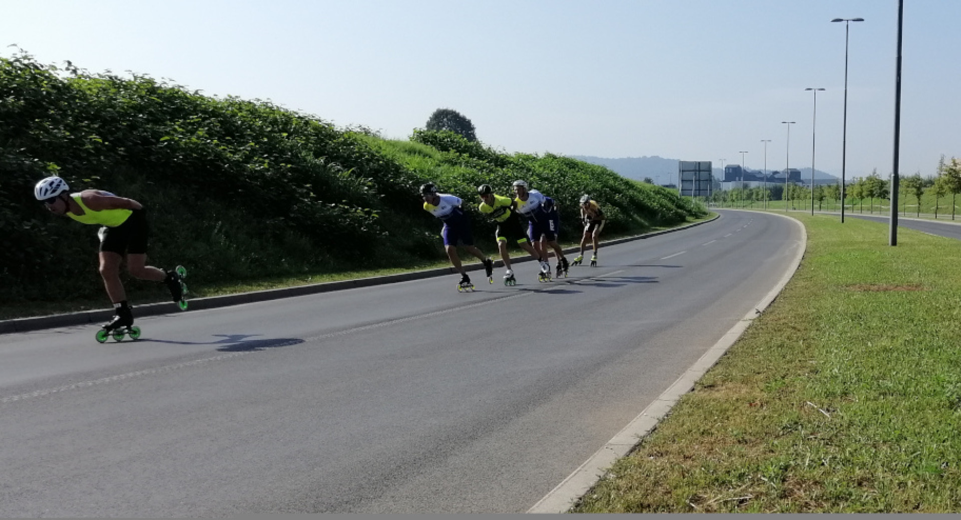 Rollerbladers are skating down a closed, empty road on their rollerblades.