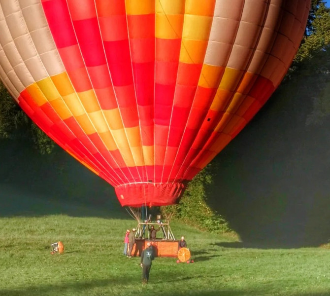 Decollo di una mongolfiera, con alberi verdi sullo sfondo.